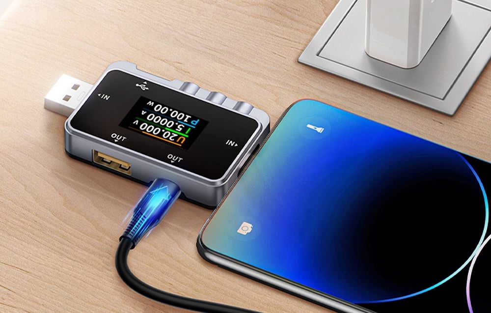 Smartfon leży na blacie podłączony do testera USB.