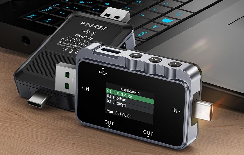 Testery USB leżą na blacie oparte o laptop.