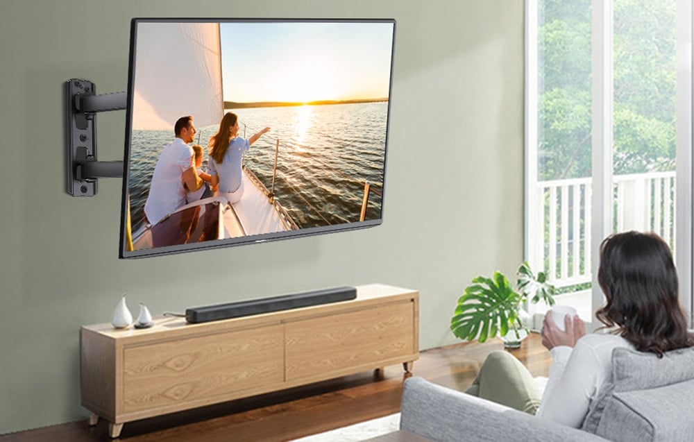 Kobieta ogląda telewizor z zamontowanym uchwytem ściennym, siedząc na kanapie w jasnym salonie