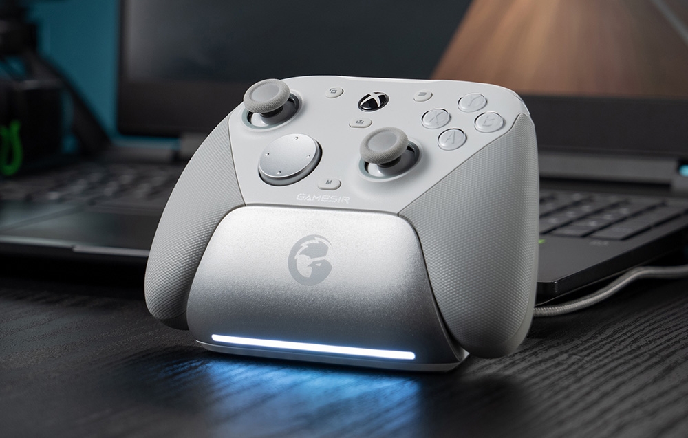 Λευκό χειριστήριο GameSir σε σταθμό σύνδεσης τοποθετημένο μπροστά από φορητό υπολογιστή.