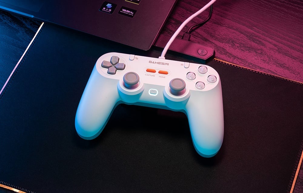 Λευκό ενσύρματο χειριστήριο GameSir συνδεδεμένο σε φορητό υπολογιστή και ξαπλωμένο σε μαξιλάρι.