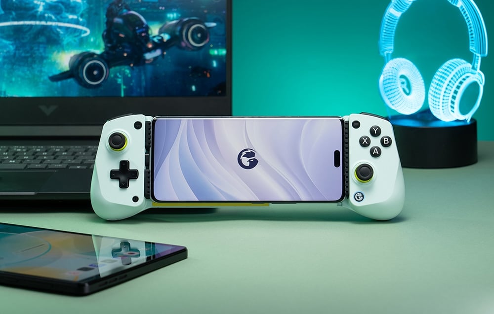 Smartphone τοποθετημένο σε λευκό χειριστήριο GameSir μπροστά από φορητό υπολογιστή και φως σε σχήμα ακουστικού.