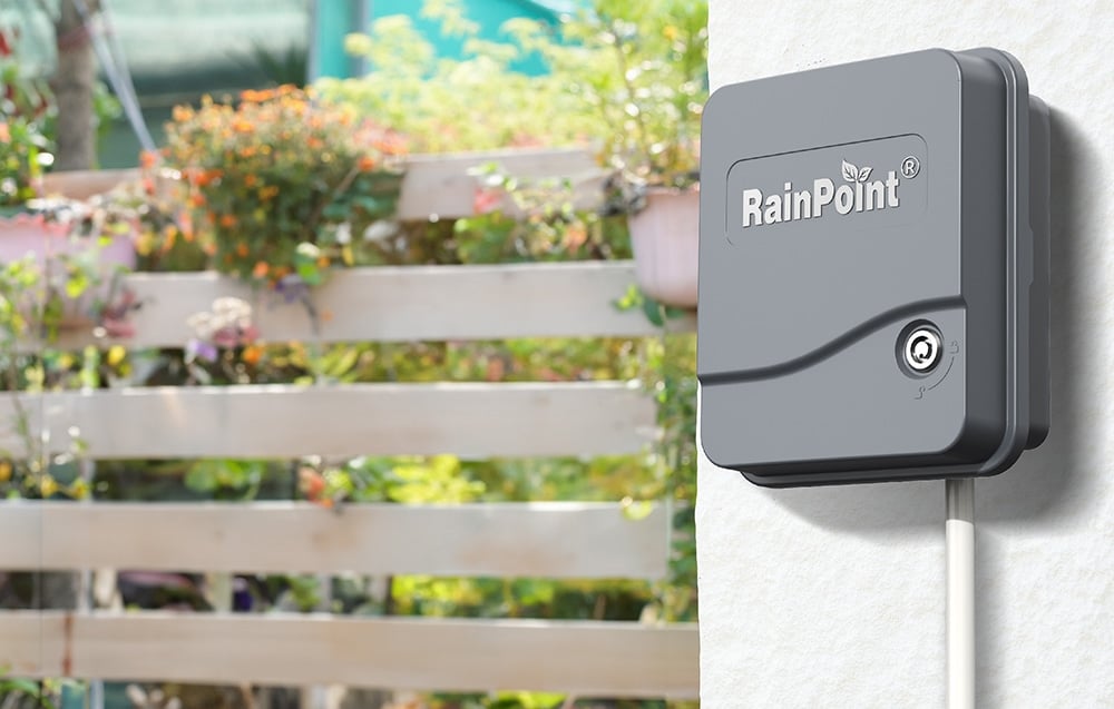 Κλειστό χειριστήριο RainPoint τοποθετημένο στον τοίχο με θέα τον κήπο στο βάθος.