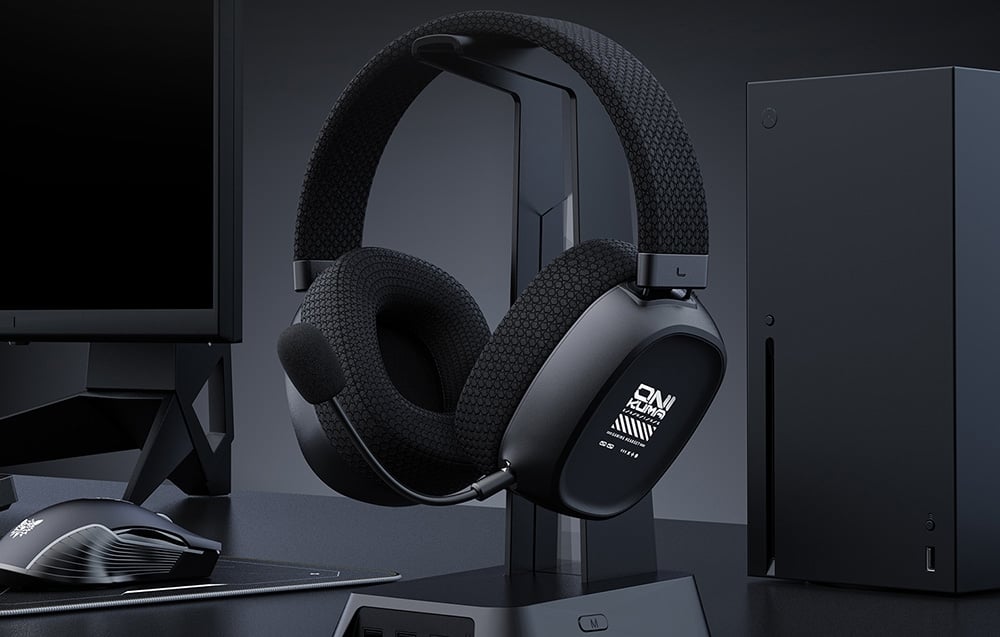 Μαύρα ακουστικά gaming σε βάση δίπλα στην κονσόλα και την οθόνη στο γραφείο