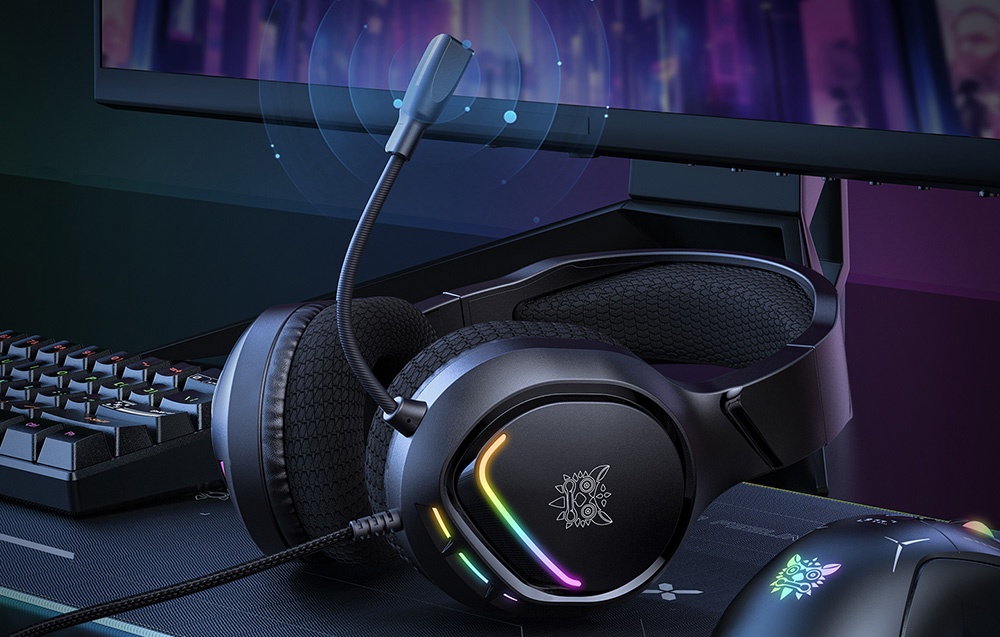 Ακουστικά με οπίσθιο φωτισμό RGB ξαπλωμένα στο γραφείο δίπλα στο πληκτρολόγιο και την οθόνη