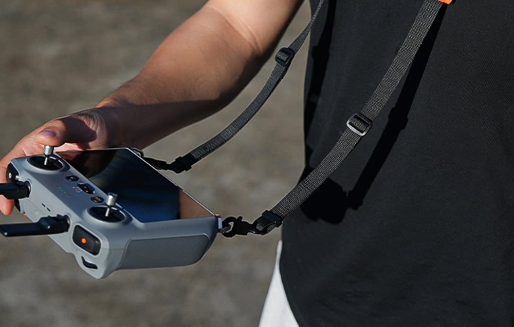 Άτομο που κρατάει συσκευή ελέγχου για drone αναρτημένη από μαύρο ιμάντα