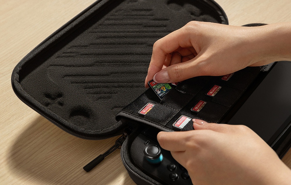 Χέρια που τοποθετούν κασέτες παιχνιδιών Nintendo Switch στη μαύρη θήκη