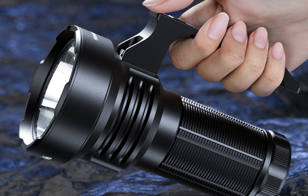 Ένα χέρι κρατά έναν μεγάλο μαύρο φακό με ευρύ ανακλαστήρα και σώμα με υφή σε μπλε φόντο.