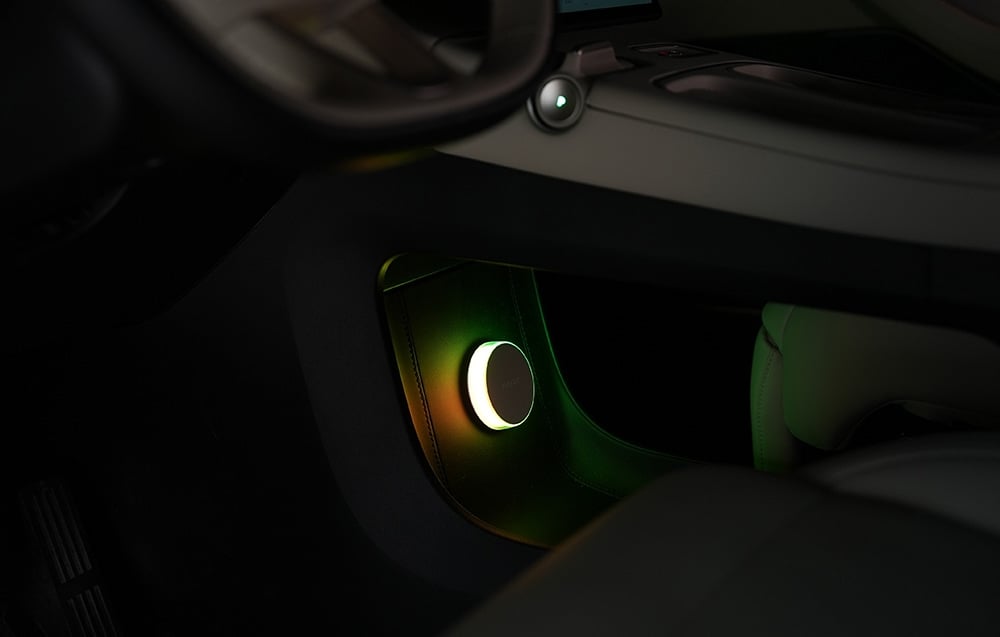 Φωτιστικό Yeelight Vega κομοδίνο τοποθετημένο στο κάτω μέρος του ταμπλό του αυτοκινήτου, φωτιζόμενο με πράσινο-κίτρινο φως.