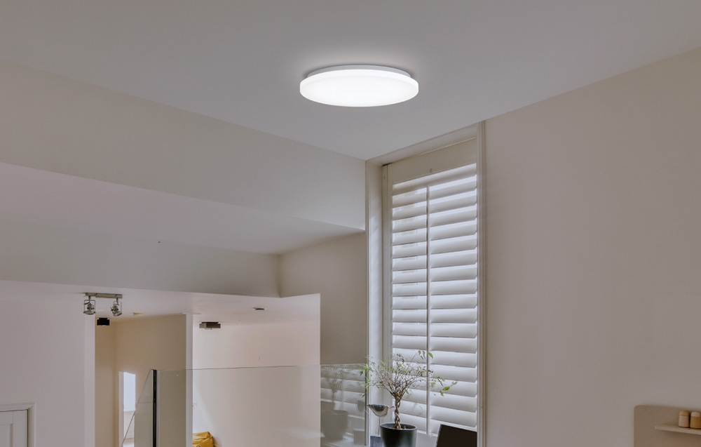 Λαμπτήρας Yeelight MercuryE C260 τοποθετημένος σε εσωτερικό χώρο με κατακόρυφες περσίδες και μια γλάστρα στο περβάζι του παραθύρου.