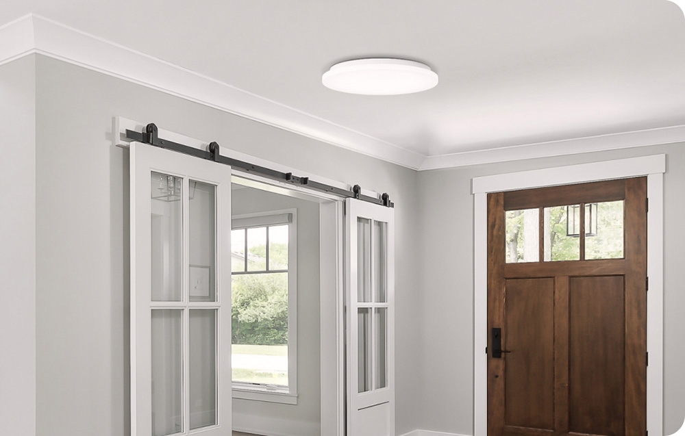 Λαμπτήρας οροφής Yeelight MercuryE C300 τοποθετημένος σε φωτεινό διάδρομο με συρόμενες πόρτες και ξύλινη εξώπορτα.