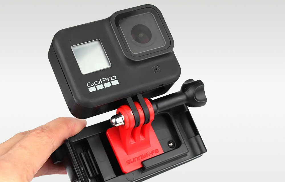 Χέρι που κρατάει το κλιπ της κάμερας GoPro, δείχνοντας πώς είναι τοποθετημένη στον ιμάντα του σακιδίου πλάτης