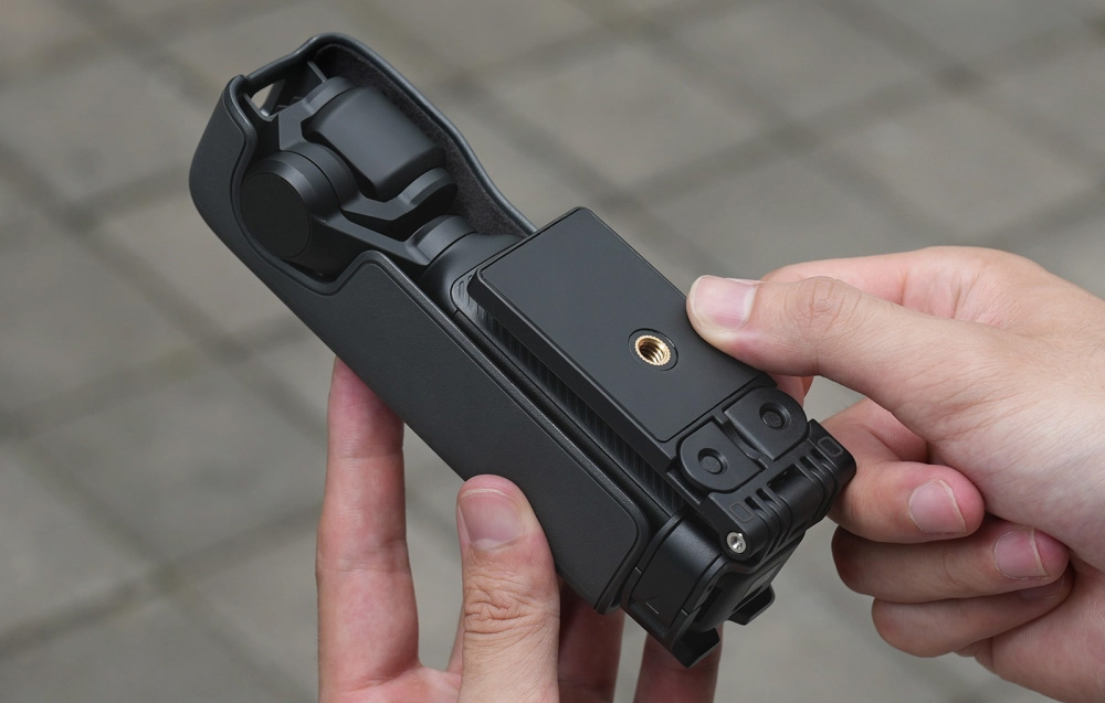 Ένα άτομο που κρατάει μια διπλωμένη κάμερα DJI Pocket με το μαγνητικό στήριγμα με το νήμα εγκατεστημένο