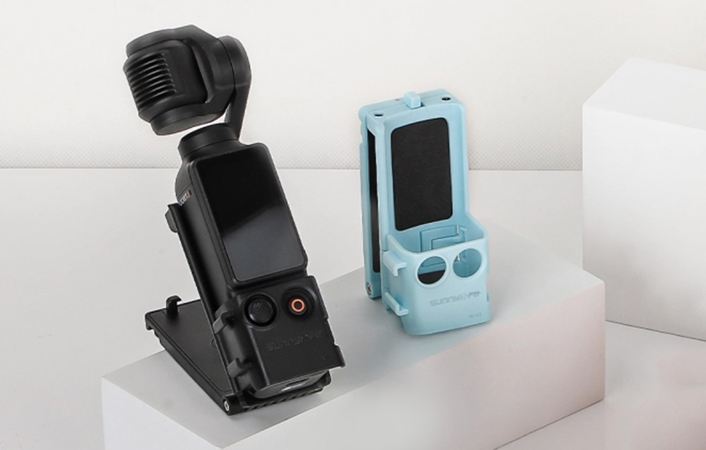 Κάμερα DJI Pocket τοποθετημένη στη μαύρη βάση στήριξης Sunnylife δίπλα στην κενή μπλε έκδοση της βάσης στήριξης