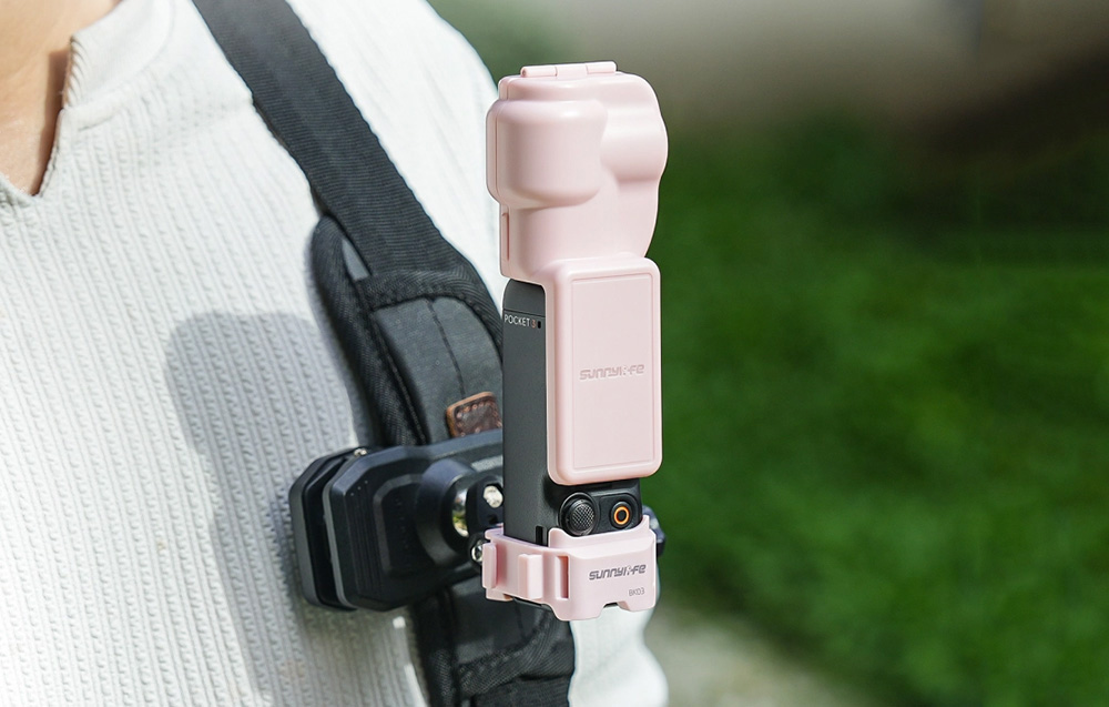 Κάμερα DJI Pocket τοποθετημένη σε ροζ θήκη Sunnylife και προσαρτημένη σε ιμάντα σακιδίου πλάτης χρησιμοποιώντας το στήριγμα