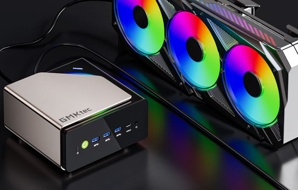 Το mini PC της GMKtec βρίσκεται πάνω σε ένα μαύρο τραπέζι. Δίπλα σε 3 έγχρωμους ανεμιστήρες.