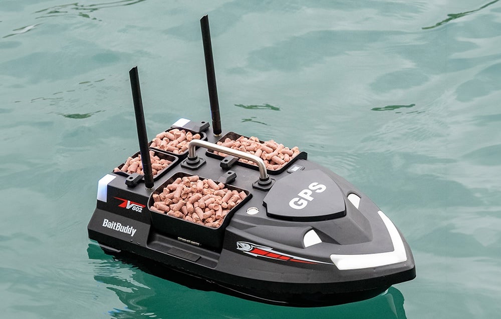 BaitBuddy βάρκα δολωμάτων με ροζ σφαιρίδια σε δοχεία που επιπλέουν σε διαυγές τυρκουάζ νερό, γράμματα GPS