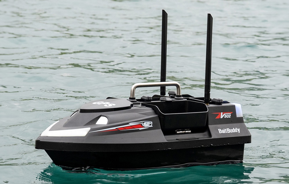 BaitBuddy V602 RC βάρκα δολωμάτων με δύο κεραίες που επιπλέει στο ήρεμο πρασινωπό νερό της λίμνης