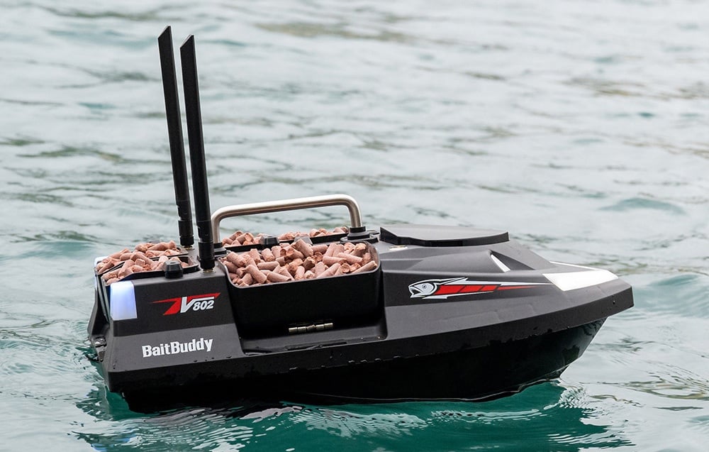 BaitBuddy V602 RC βάρκα δολωμάτων με ροζ σφαιρίδια που επιπλέουν σε καθαρό τυρκουάζ νερό