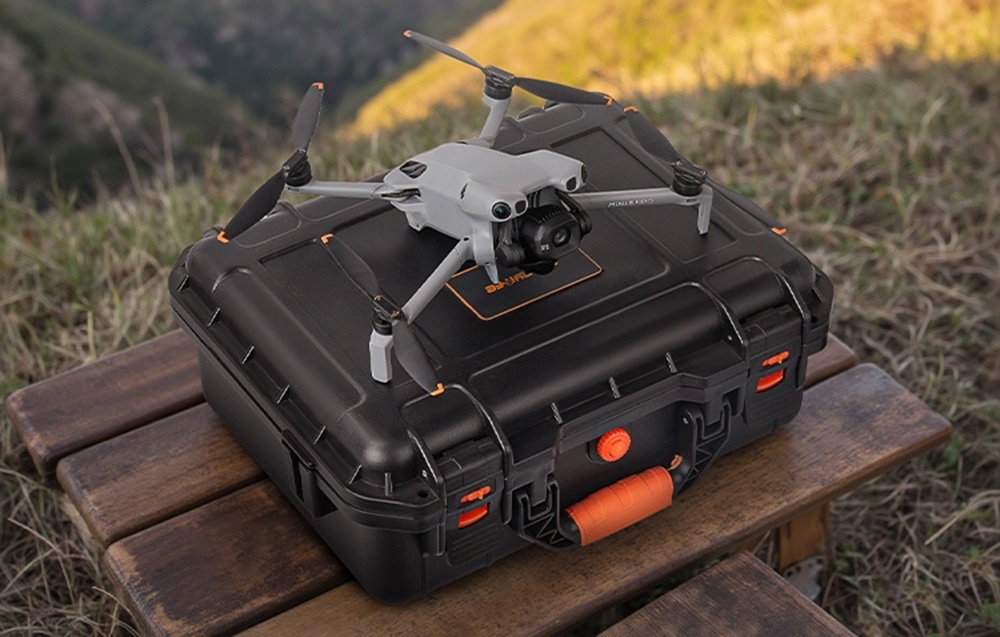 Η προστατευτική θήκη με το drone DJI Mini 5 Pro από πάνω βρίσκεται σε ένα παγκάκι στο γρασίδι.