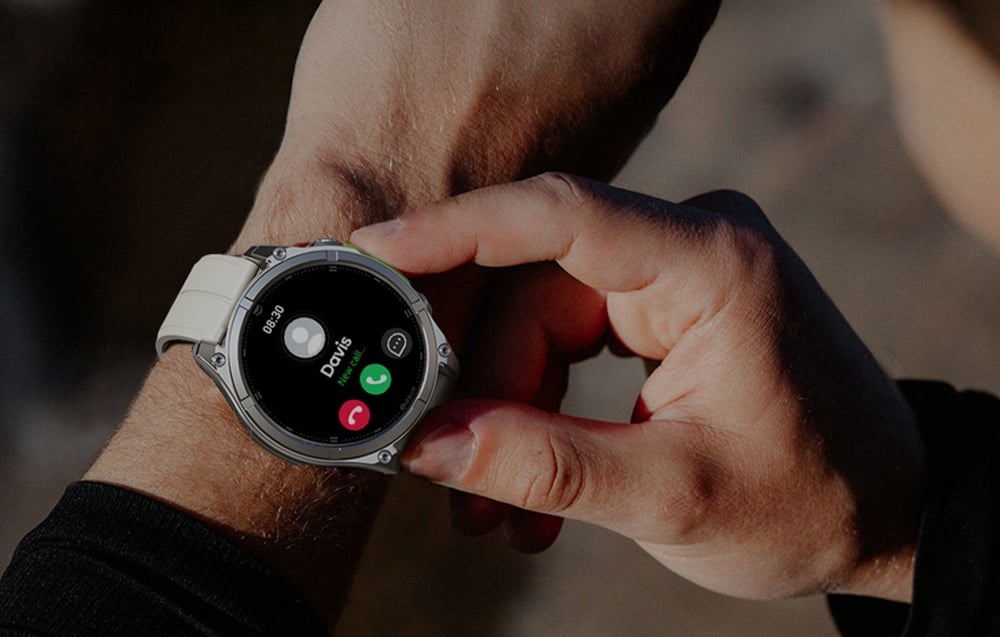 Χέρι που κρατά smartwatch με λευκό λουράκι, οθόνη εισερχόμενης κλήσης ορατή στο καντράν