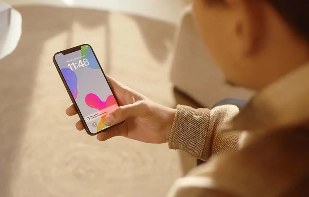 Γυναίκα ξεκλειδώνει την πόρτα χρησιμοποιώντας την εφαρμογή iPhone - η οθόνη εμφανίζει ειδοποίηση ότι η κλειδαριά έχει ανοίξει