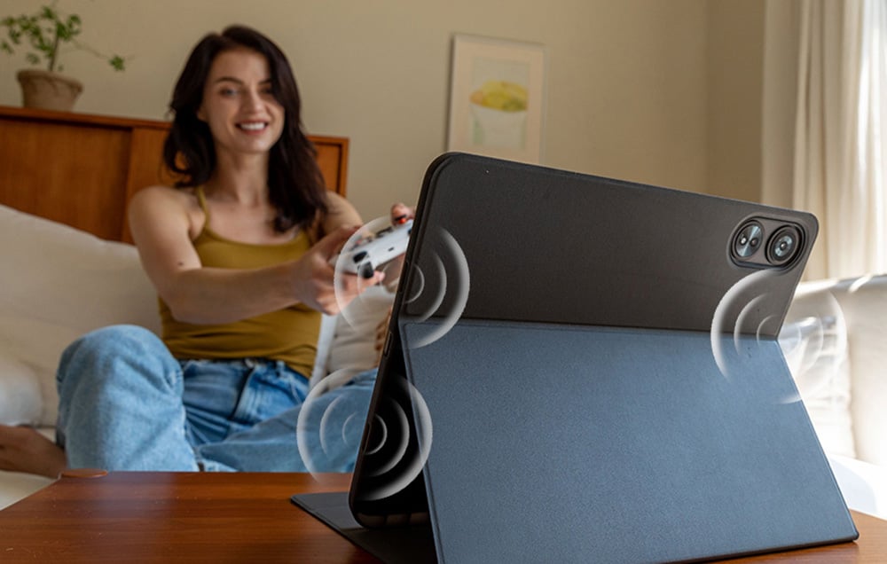 Μια γυναίκα που παίζει με ένα tablet pad μέσα σε μια θήκη με ηχητικές σφραγίδες που δείχνουν στερεοφωνικά ηχεία