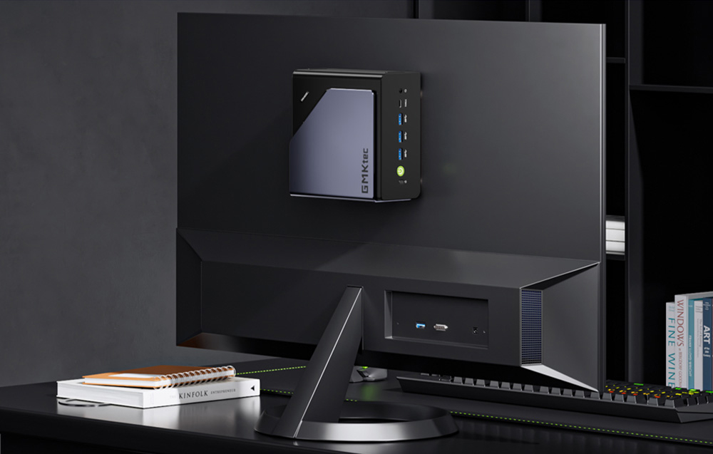 Μίνι PC GMKtec τοποθετημένο στο πίσω μέρος μιας οθόνης σε ένα σύγχρονο μαύρο γραφείο