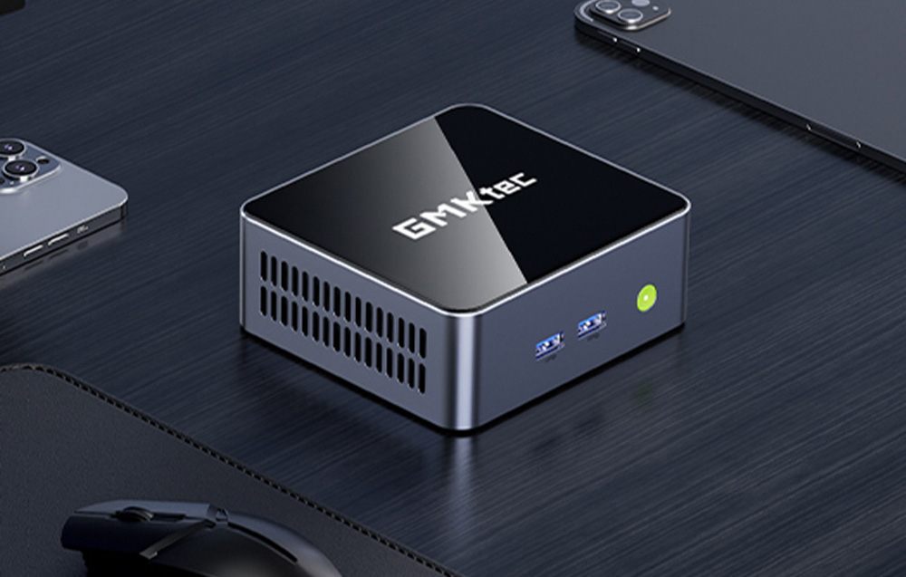 GMKtec mini PC με γυαλιστερό φινίρισμα στο γραφείο δίπλα στο ποντίκι, το τηλέφωνο και το φορητό υπολογιστή