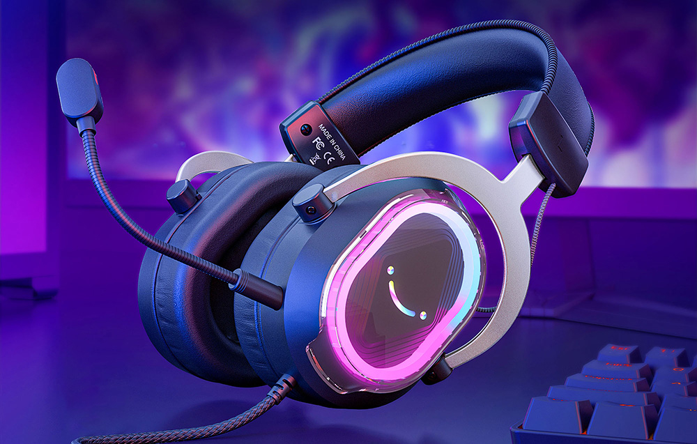 Μαύρα ακουστικά με μικρόφωνο και ροζ RGB οπίσθιο φωτισμό που βρίσκονται στο γραφείο δίπλα στο πληκτρολόγιο.