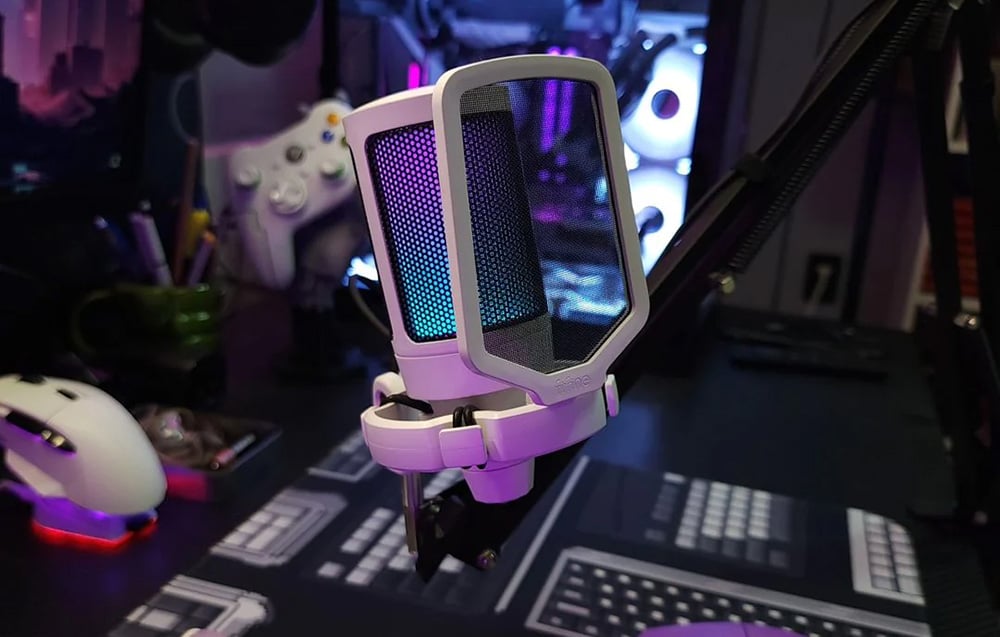 Λευκό μικρόφωνο gaming με φίλτρο pop, στο βάθος η βάση gaming