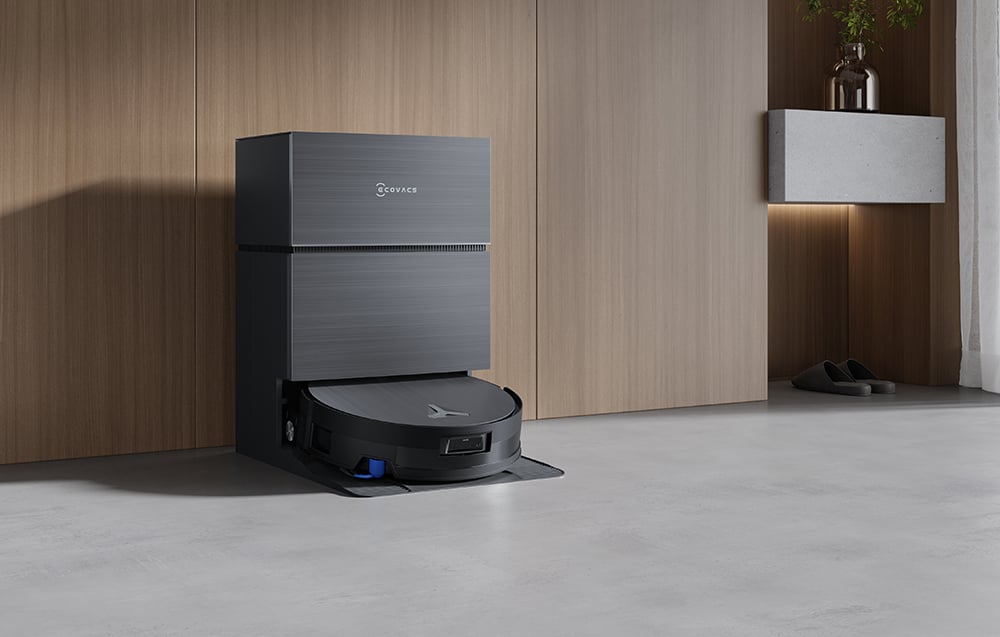 Σταθμός σύνδεσης με το ρομπότ καθαρισμού Deebot X11 PRO OMNI που ακουμπά σε ένα ξύλινο ντουλάπι