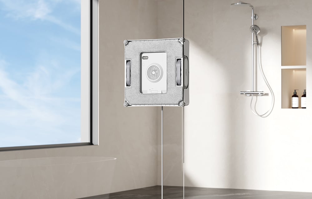 Το ρομπότ Ecovacs W2 Pro πλένει το τζάμι του ντους, στα αριστερά υπάρχει ένα παράθυρο