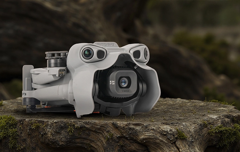 Ένα διπλωμένο μη επανδρωμένο αεροσκάφος DJI Mini 5 Pro με το κάλυμμα του αρθρωτού τροχού, που βρίσκεται πάνω σε έναν κορμό δέντρου