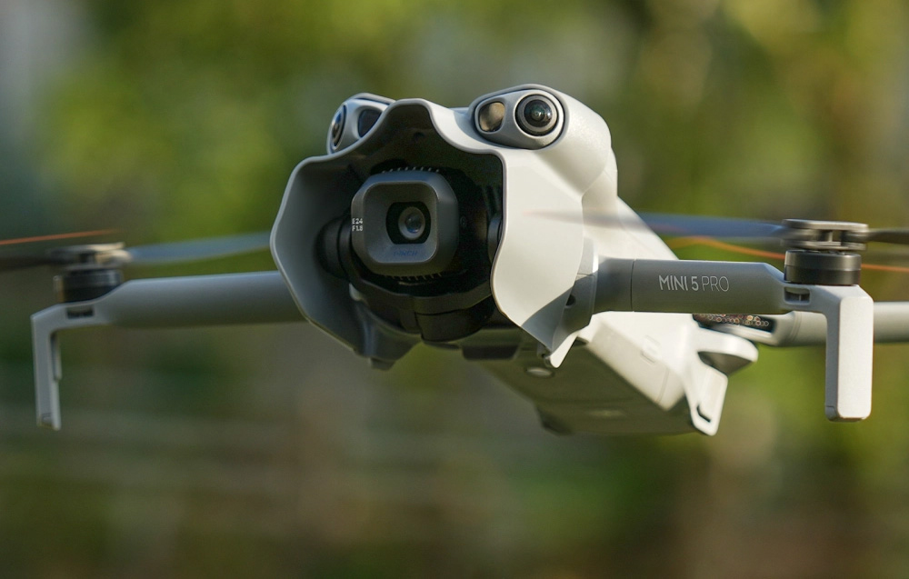 DJI Mini 5 Pro drone σε πτήση με τοποθετημένο το χαρακτηριστικό γκρι ανοιχτό γκρι κάλυμμα του gimbal