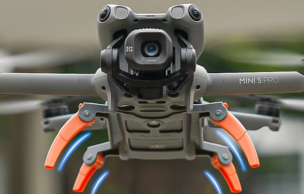 Κάτω όψη του drone DJI Mini 5 Pro με τα πορτοκαλί επεκτεινόμενα πόδια προσγείωσης τοποθετημένα
