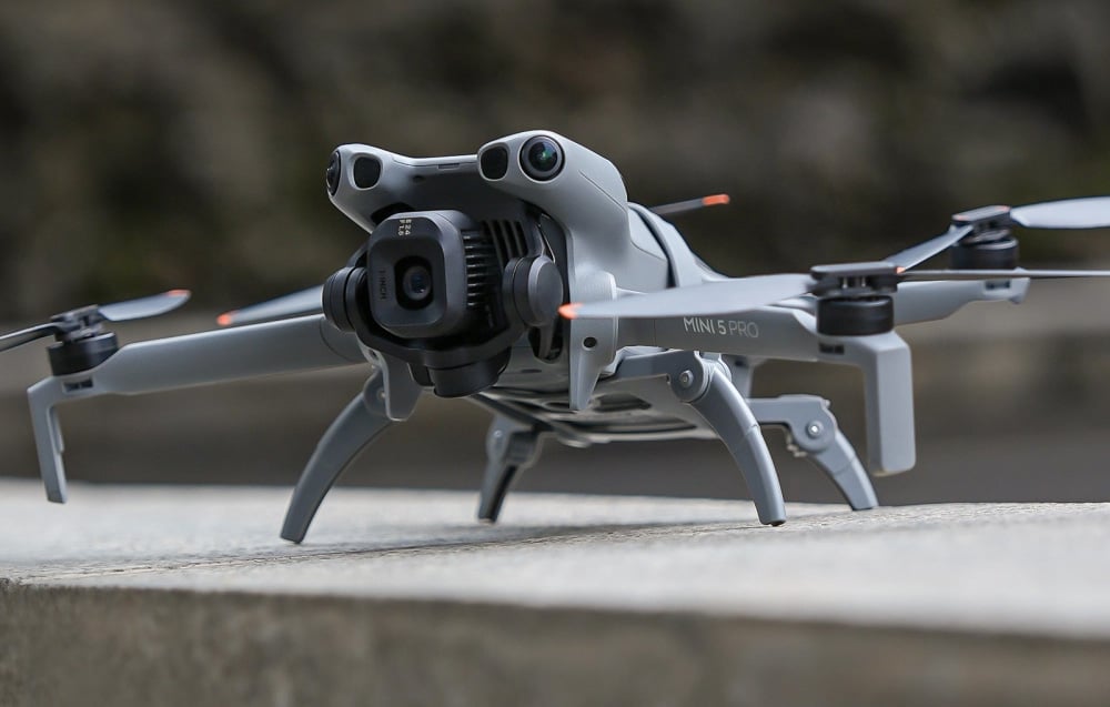 DJI Mini 5 Pro drone άνω σε επιφάνεια από σκυρόδεμα με απλωμένα πόδια για προσγείωση