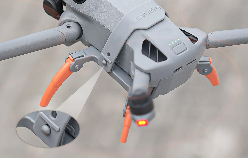 Αεροφωτογραφία του πίσω μέρους του drone DJI Mini 5 Pro με τα πορτοκαλί πόδια τοποθετημένα και ζουμ του μηχανισμού στερέωσης σε κοντινό πλάνο