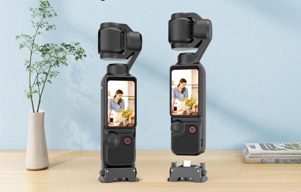 Δύο κάμερες Osmo Pocket 3 με τοποθετημένους προσαρμογείς Puluz που στέκονται σε ένα ξύλινο τραπέζι δίπλα σε ένα βάζο με ένα λουλούδι