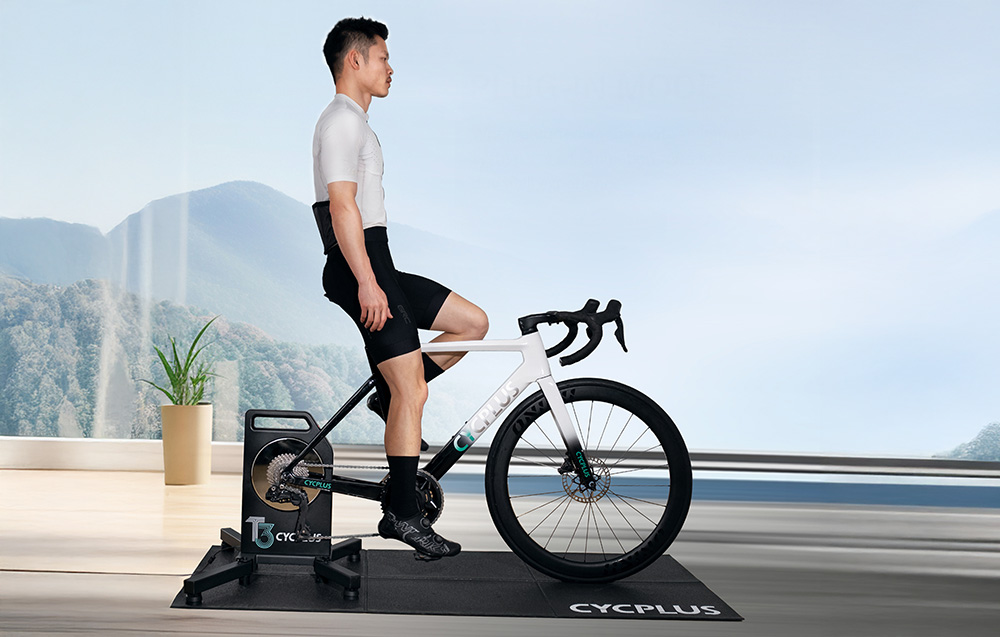 Ένα άτομο πάνω σε έναν προπονητή Cycplus T3 με πανοραμική θέα στα βουνά