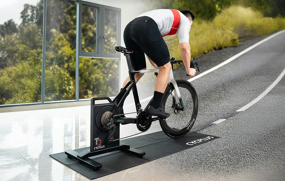 Ποδηλάτης Cycplus που προπονείται στον προπονητή Cycplus με προσομοίωση ανηφόρας σε ασφάλτινο δρόμο