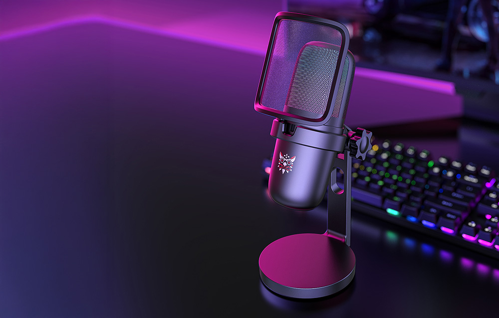 Μαύρο μικρόφωνο gaming Onikuma στο γραφείο, πληκτρολόγιο και οθόνη σε απόσταση