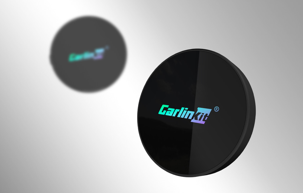 Δύο ασύρματοι προσαρμογείς Carlinkit, ο ένας καθαρός στο προσκήνιο, ο άλλος θολωμένος στο παρασκήνιο.