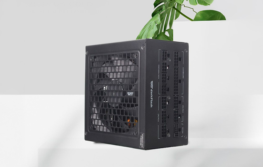 Μαύρο τροφοδοτικό DarkFlash σε λευκό πάγκο με πράσινο φυτό στο φόντο