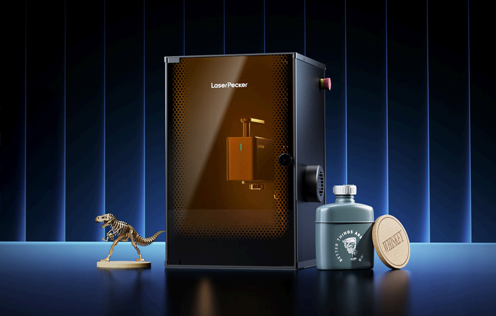 Λέιζερ χάραξης LaserPecker LP2 Plus σε μπλε φόντο δίπλα σε ένα ξύλινο φιγούρα δεινόσαυρου και ένα μπουκάλι.