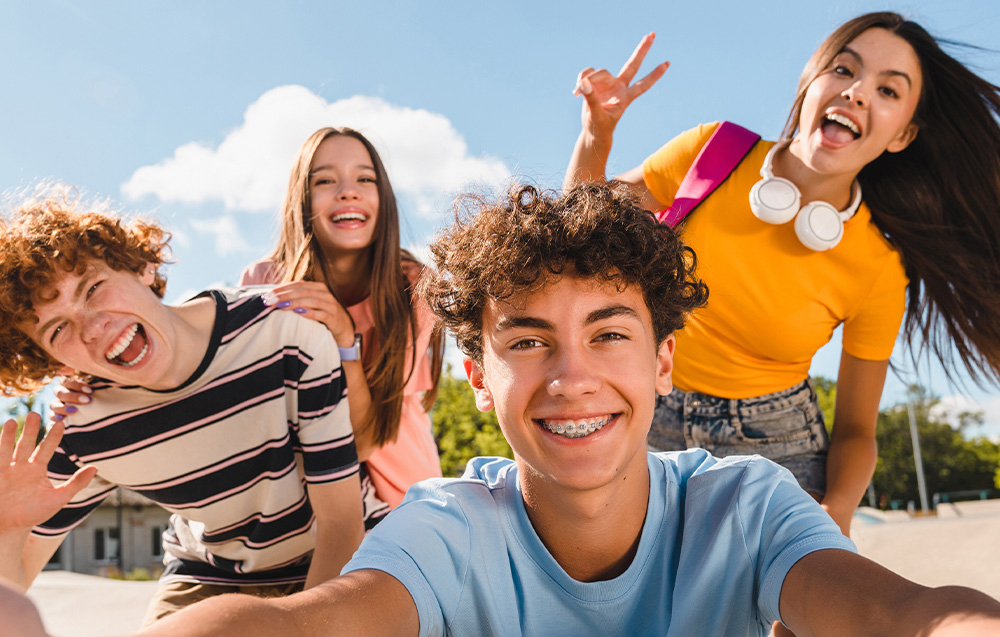 Τέσσερις νέοι που τραβούν μια selfie με φόντο έναν συννεφιασμένο ουρανό