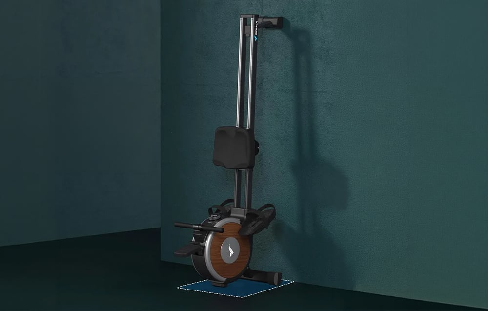 Κωπηλατική μηχανή Merach διπλωμένη κάθετα για αποθήκευση, ακουμπισμένη σε σκούρο πράσινο τοίχο