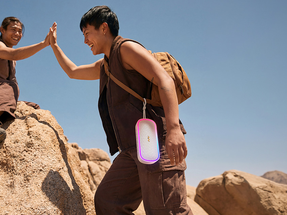 Άτομο με σακίδιο που μεταφέρει ένα ηχείο Bluetooth κατά τη διάρκεια πεζοπορίας