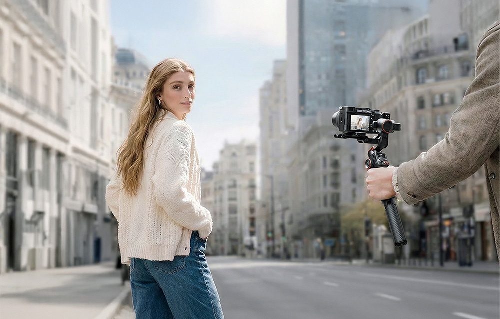 Ένα άτομο με gimbal και κάμερα που βιντεοσκοπεί ένα κορίτσι σε έναν δρόμο της πόλης