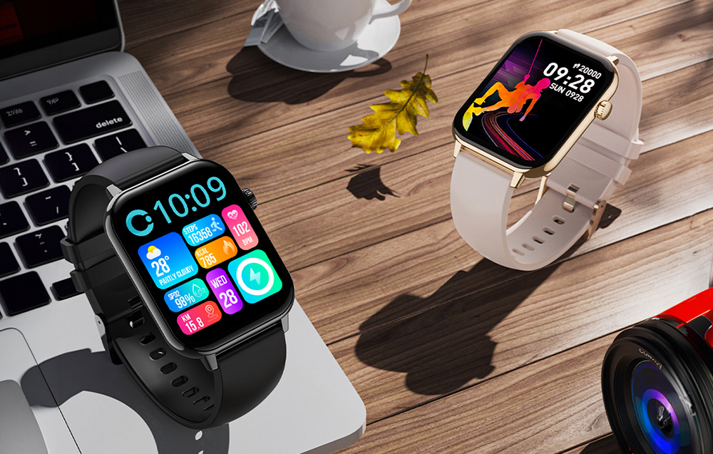 Δύο smartwatch Colmi (μαύρο και χρυσό) πάνω σε ξύλινο γραφείο με φορητό υπολογιστή και καφέ
